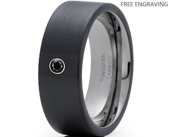 May include: A black tungsten carbide ring with a brushed finish and a single black diamond set in the center. The ring is engraved with "TUNGSTEN CARBIDE" on the inside.