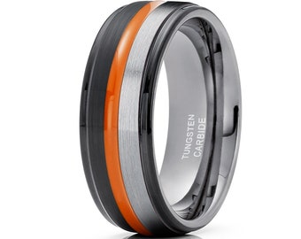 May include: A black tungsten carbide ring with an orange and silver inlay. The ring has a beveled edge and is engraved with "TUNGSTEN CARBIDE".