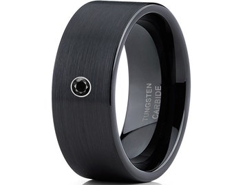 May include: A black tungsten carbide ring with a brushed finish. The ring features a small, round black gemstone and the text "TUNGSTEN CARBIDE" is engraved on the side. The ring has a polished interior.