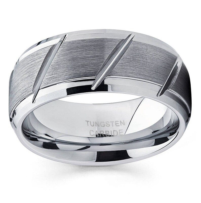 May include: A silver tungsten carbide ring with a brushed finish and diagonal grooves. The ring is engraved with "TUNGSTEN CARBIDE".