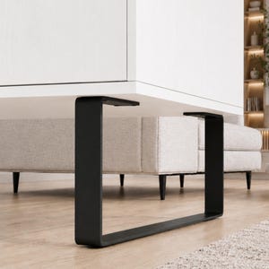 Könnte beinhalten: Ein moderner weißer Schrank mit einem schwarzen Metallrahmen. Der Schrank hat eine hellfarbige gepolsterte Basis und steht auf einem hellen Holzboden. Der schwarze Rahmen hat eine rechteckige Form.