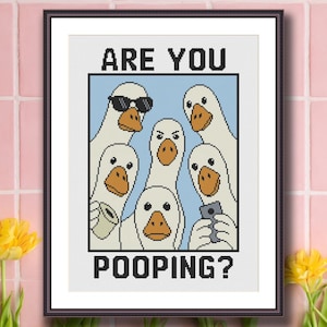 Puede incluir: Impresión artística en punto de cruz enmarcada que muestra un grupo de gansos con diferentes expresiones. Un ganso lleva gafas de sol y otro sostiene un teléfono. El texto "ARE YOU POOPING?" se muestra debajo.