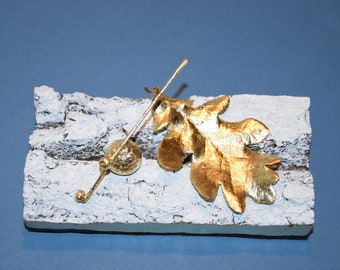 Oak leaf and its cup, natural, gilded with the leaf on an oak bark.