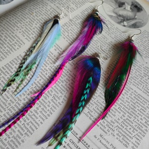 May include: Three pairs of colourful feather earrings with pink, blue, green, and white feathers. The earrings are handmade and feature a variety of feather textures.