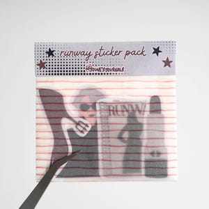 Peut inclure: Un paquet d'autocollants transparents avec un fond rayé rouge et blanc. Le paquet contient des autocollants sur le thème de la mode, dont un magazine avec le mot "RUNWAY" et une silhouette d'une personne. Le haut du paquet indique "runway sticker pack" avec des étoiles.