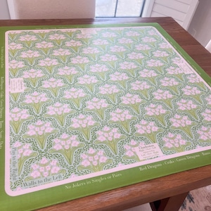 May include: A green and pink patterned game board with text. The board features a repeating floral design in pink and green on a light green background. The border is green, and the text includes "Walls to the Left" and "Play to the Right."