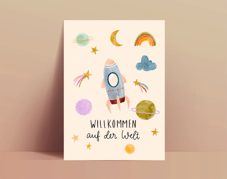 May include: Watercolor illustration featuring a rocket ship, planets, stars, a rainbow, and a crescent moon. The text "WILLKOMMEN auf der Welt" is displayed in a whimsical font. The artwork has a soft, pastel color palette.