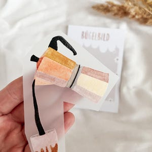 Könnte beinhalten: Ein transparenter Aufkleber mit einer Aquarell-Illustration einer Kaffeekanne, die Kaffee in eine Tasse gießt. Die Kaffeekanne ist braun, orange und gelb. Die Tasse ist braun und weiß.