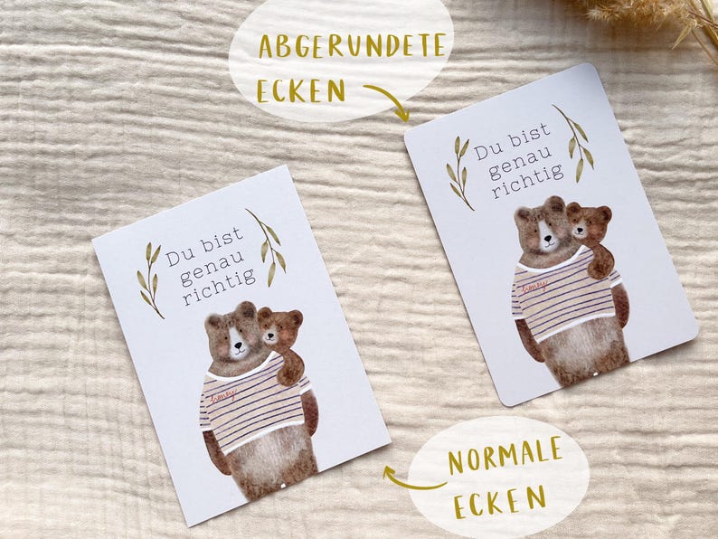 May include: Two white cards with a watercolor illustration of two bears. The larger bear wears a striped shirt and embraces a smaller bear. The text "Du bist genau richtig" is above the bears.