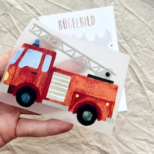 Könnte beinhalten: Ein rotes Feuerwehrauto als Bügelbild mit einer langen silbernen Leiter, hellblauen Fenstern und schwarzen Rädern. Das Motiv hat eine texturierte, gemalte Optik. Im Hintergrund ist eine weiße Karte mit dem Text BÜGELBILD in braunen Buchstaben zu sehen.