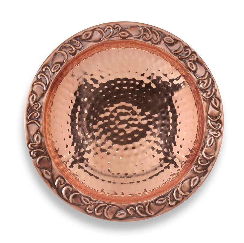 May include: A hammered copper bowl with a decorative floral design around the rim. The bowl is a deep copper color and has a shiny finish.