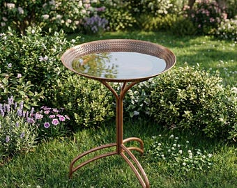 May include: A copper-colored metal bird bath featuring a circular basin with a textured, dotted rim. The basin is filled with water and is supported by a slender, three-legged stand that curves outward at the base to provide stability on the ground.