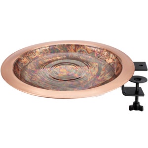 May include: Copper bird bath with a rippled surface and a black metal clamp for attaching to a pole or railing.