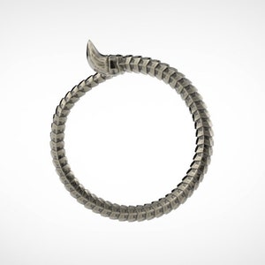 May include: A silver-colored bracelet in the shape of a snake. The bracelet is made of interlocking, textured segments, with a raised head and a curved tail. The design is detailed and appears to be made of metal.