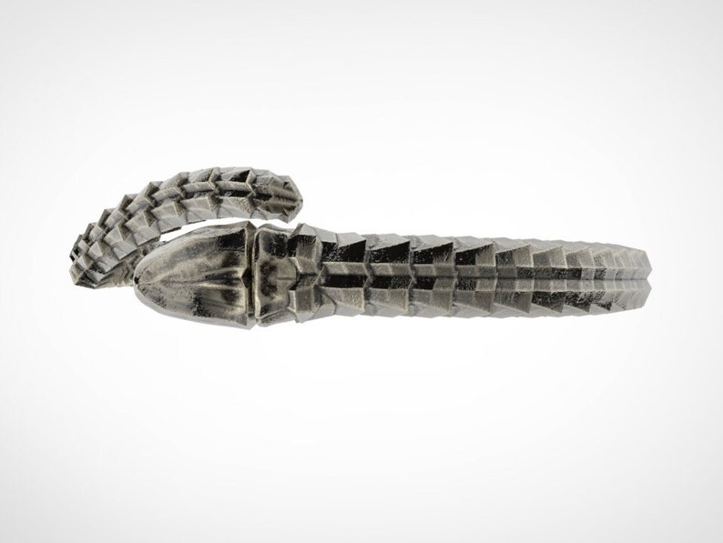 May include: A silver-colored, textured bracelet with a geometric design. The bracelet appears to be made of metal and has a detailed, scale-like pattern. The design wraps around the wrist, creating a unique accessory.