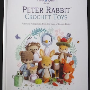 May include: A book cover featuring the title "Peter Rabbit Crochet Toys" with various crochet amigurumi characters. The cover includes a collection of adorable, handmade crochet toys, including rabbits, bears, and other woodland creatures, all in vibrant colors.