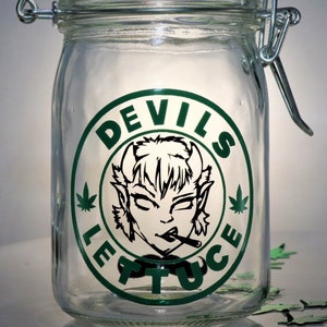 May include: A clear glass jar with a metal latch closure. The jar has a green and white sticker with the words "Devil's Lettuce" and a cartoon image of a devil with horns and a cigarette.