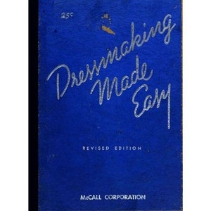 May include: A blue book cover with the title "Dressmaking Made Easy" in silver lettering. The book is a revised edition and is published by McCall Corporation.