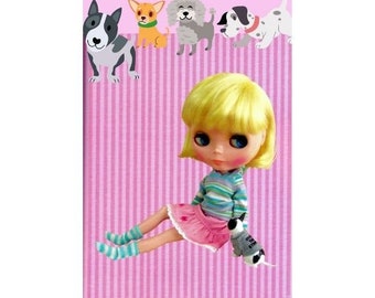 May include: A doll with blonde hair and blue eyes is wearing a pink and blue striped shirt, a pink skirt, and blue and white striped socks. The doll is holding a small gray and white stuffed animal. The doll is sitting on a pink and white striped background.