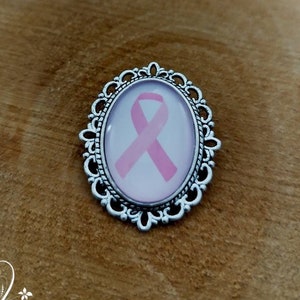 Oval or round pin brooch against the fight against breast cancer, pink ribbon, pink October.