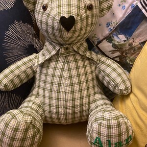 May include: A green and white plaid teddy bear with a black heart nose and the name "Alan" embroidered on one foot.
