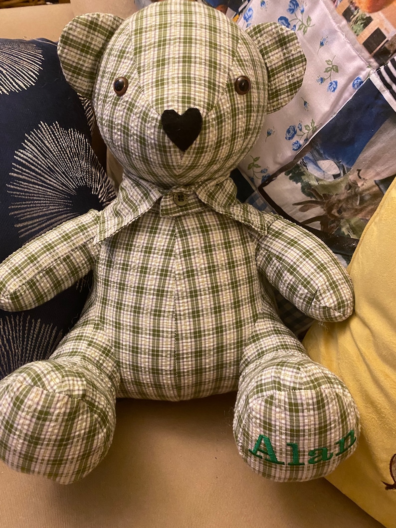 May include: A green and white plaid teddy bear with a black heart nose and the name "Alan" embroidered on one foot.