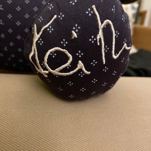 May include: A black fabric stuffed toy with a white embroidered name "Keith" on it.