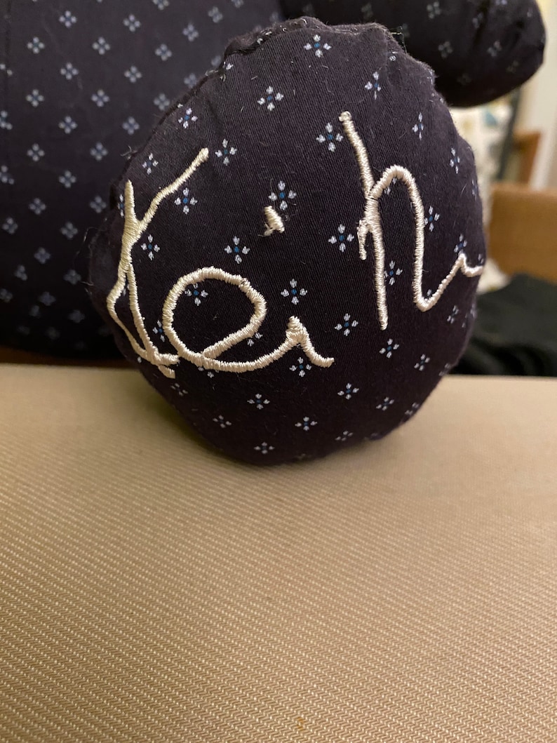 May include: A black fabric stuffed toy with a white embroidered name "Keith" on it.