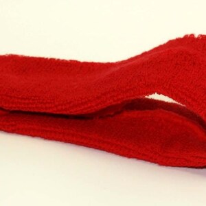 Peut inclure: Un bandeau rouge en tissu doux et extensible. Il est pli&eacute; en deux et pos&eacute; sur une surface blanche.