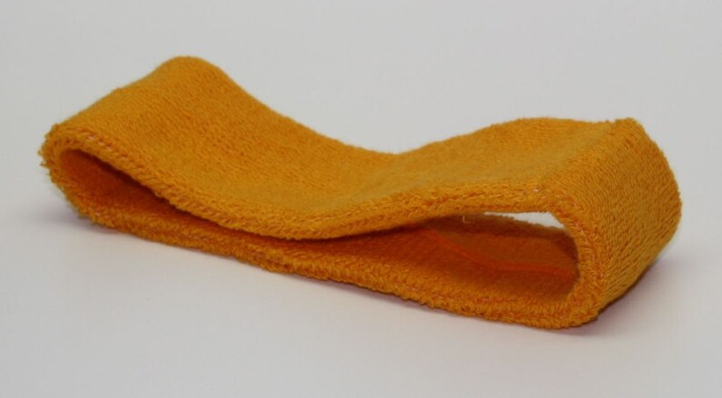 Peut inclure: Un bandeau jaune vif en tissu doux et extensible. Le bandeau est pli&eacute; en deux et pr&ecirc;t &agrave; &ecirc;tre port&eacute;.