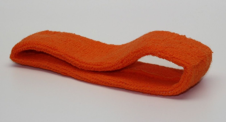 Peut inclure: Un bandeau orange en tissu doux et extensible. Le bandeau est pli&eacute; en deux et pr&ecirc;t &agrave; &ecirc;tre port&eacute;.