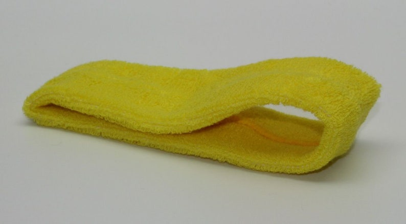 Peut inclure: Un bandeau jaune en tissu doux et absorbant. Il est con&ccedil;u pour &ecirc;tre port&eacute; autour du front afin d'absorber la transpiration et de garder les cheveux hors du visage.