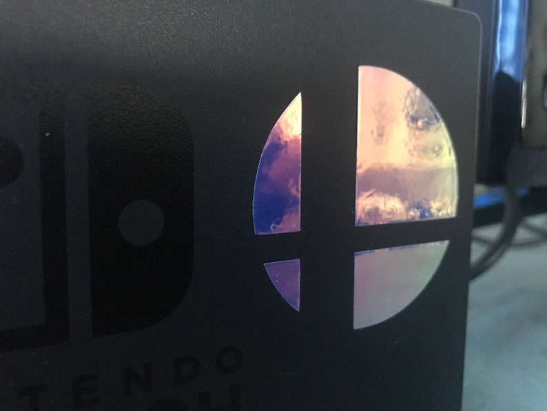 May include: A black Nintendo Switch game case with a holographic Super Smash Bros. logo.