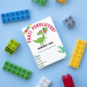 May include: A white card with a dinosaur illustration and the text "PARTI PENBLWYDO!" and "GWAHODDIAD I BARTI:"  The card has a list of information to fill in, including date, time, location, RSVP by, and phone number.