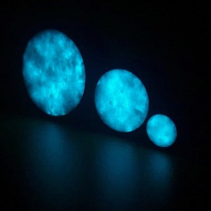 May include: Three round, glowing, blue and white, resin, galaxy-themed, decorative objects of varying sizes.
