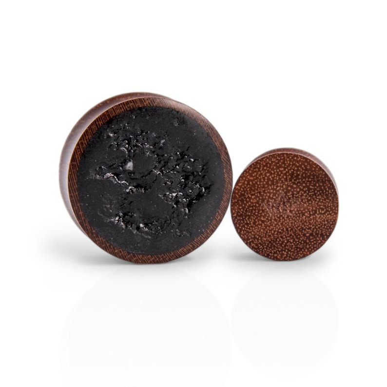 May include: A pair of wooden ear gauges, one with a black inlay and the other with a natural wood finish.