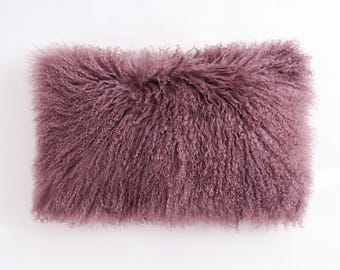 May include: A soft, plush pillow with a mauve-colored, curly sheepskin cover.