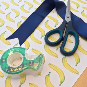Close-up of banana giftwrap with scissors and tape for size