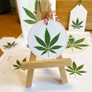 Peut inclure: Un ensemble d'étiquettes cadeaux imprimables avec un motif de feuille de marijuana verte. Les étiquettes sont imprimées sur du papier cartonné blanc et sont prêtes à être découpées et utilisées.