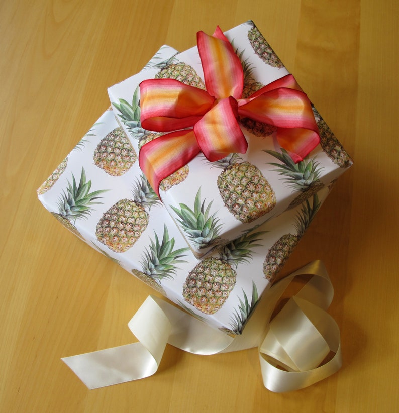 Pineapple giftwrap adorns these gifts, along with a cream silk ribbon and pink and orange bow.