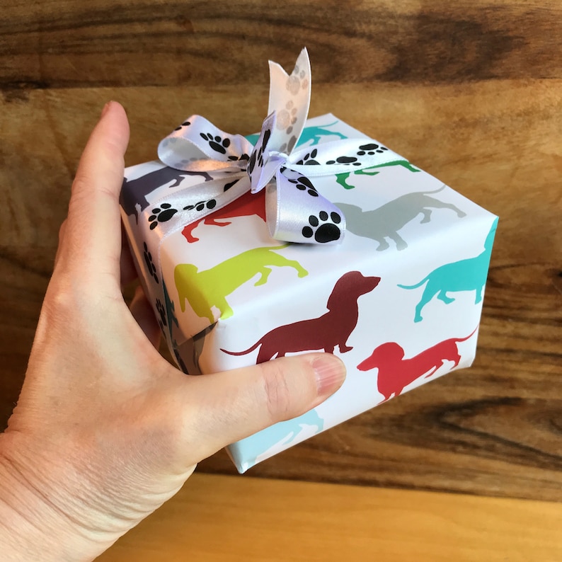 a gift wapped in colorful dachshund giftwrap with paw-print ribbon