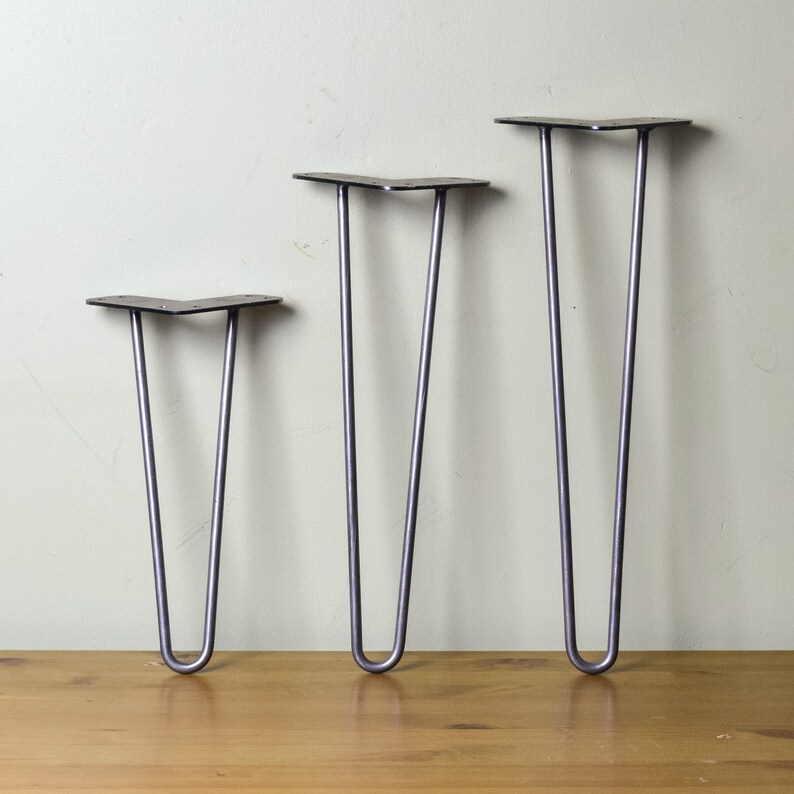 May include: Three metal hairpin legs in different sizes. The legs are silver in color and have a slight bend at the top. The legs are arranged in order of size, with the smallest leg on the left and the largest leg on the right.