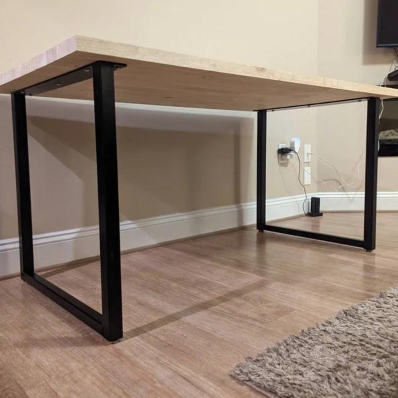 May include: A light wood table top with black metal legs. The table is in a room with wood floors and a rug.