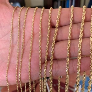 May include: A set of nine gold rope chains of varying thicknesses, displayed on a hand.