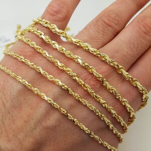 May include: A set of six gold rope chains of varying thicknesses, displayed on a hand.