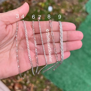 May include: A close-up of a hand holding nine different silver chains. The chains are labeled with numbers 3, 4, 6, 7, 8, and 9.