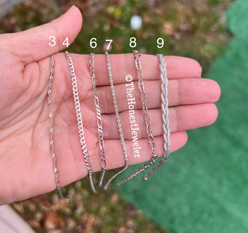 May include: A close-up of a hand holding nine different silver chains. The chains are labeled with numbers 3, 4, 6, 7, 8, and 9.