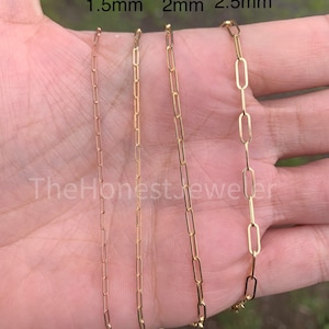 May include: Three gold chains of different sizes, 1.5mm, 2mm, and 2.5mm, are shown on a hand. The chains are made of a classic link style.