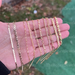 May include: A collection of ten gold chains of different styles and thicknesses, displayed on a hand.