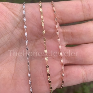May include: Three delicate gold chains with a textured oval link design. The chains are silver, gold, and rose gold.